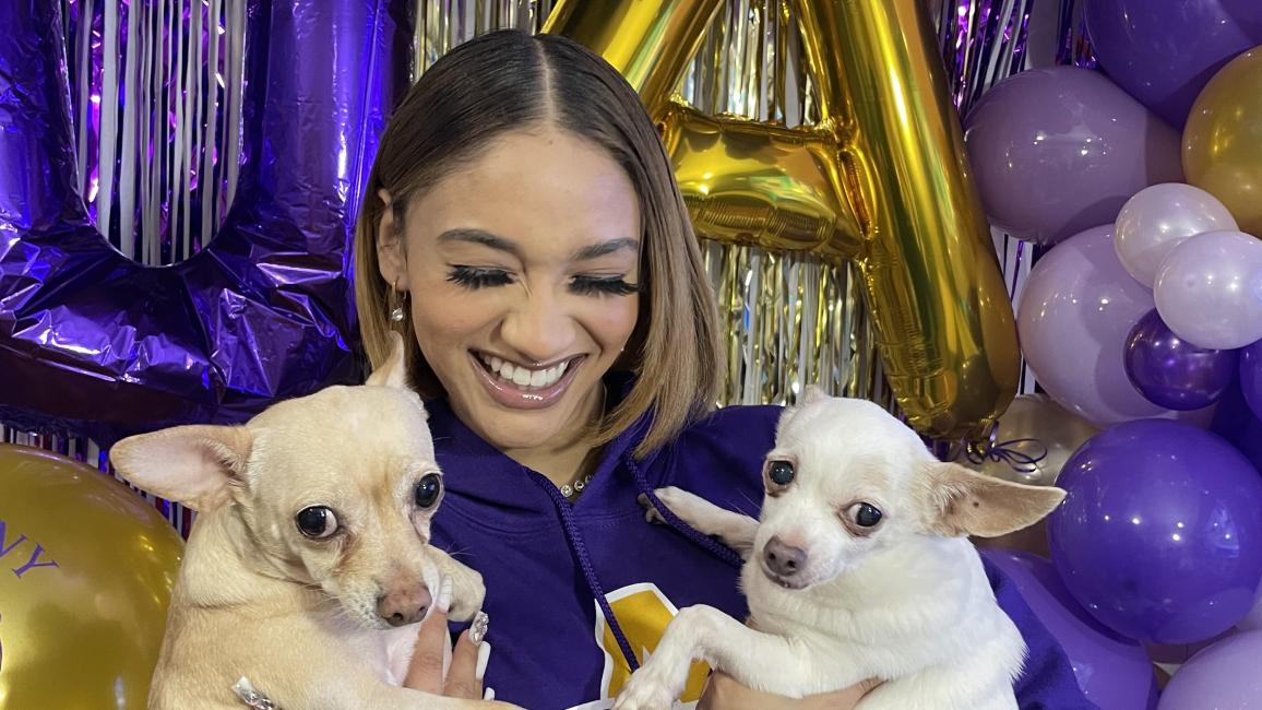 Noemi Peguero holding two Chihuahuas and surrounded by purple balloons